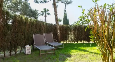a pair of chairs sitting in the grass in a yard at Estupendo Adosado Urbanizacion Hoyo 12 Novo Sancti Petri in Chiclana de la Frontera