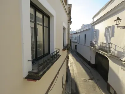 a narrow alley with windows and a balcony on a building at Casa de las Especias Hotel Boutique in Sanlúcar de Barrameda