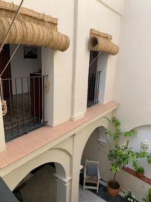 a building with a balcony with a chair and a plant at Casa de las Especias Hotel Boutique in Sanlúcar de Barrameda