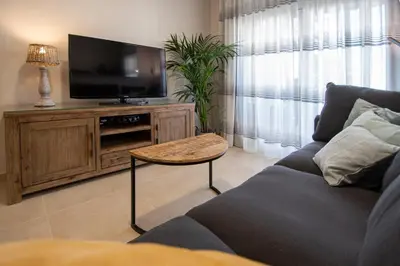 a living room with a couch and a flat screen tv at Jardines de Candelaria Cadiz in Cádiz