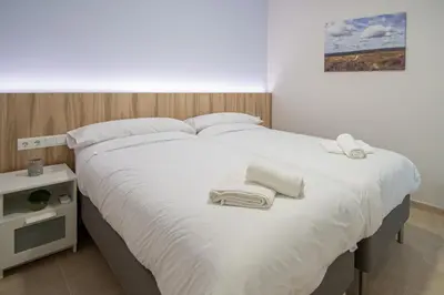 a white bed with towels on it in a bedroom at Jardines de Candelaria Cadiz in Cádiz