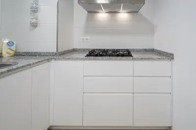 a kitchen with white cabinets and a stove at Jardines de Candelaria Cadiz in Cádiz