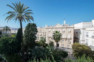 a large building with palm trees in front of it at Jardines de Candelaria Cadiz in Cádiz