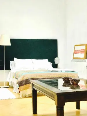 a bedroom with a bed with a green headboard and a table at Casa Bolsa43 in Sanlúcar de Barrameda
