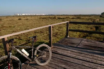 a bike parked on a wooden bridge near a field at 'Sweet home' Loft con piscina en la mejor playa de El Puerto in El Puerto de Santa María