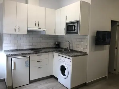 a kitchen with a washing machine and a microwave at 'Sweet home' Loft con piscina en la mejor playa de El Puerto in El Puerto de Santa María