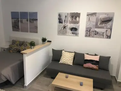 a living room with a couch and posters on the wall at 'Sweet home' Loft con piscina en la mejor playa de El Puerto in El Puerto de Santa María