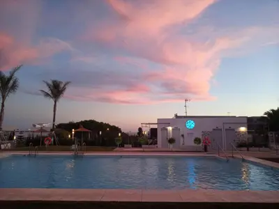 a swimming pool in front of a building with a sunset at Enjoy Selecta Conil in Conil de la Frontera
