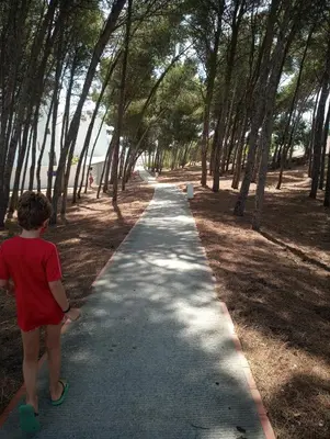 a young boy is standing on a walkway at Enjoy Selecta Conil in Conil de la Frontera