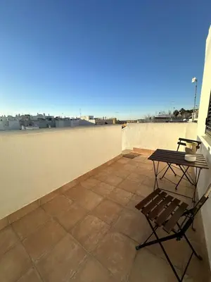 a patio with a table and a chair on a roof at Alojamiento Magallanes in Sanlúcar de Barrameda