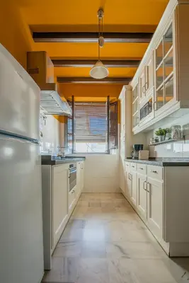 a large kitchen with white cabinets and a yellow ceiling at Apartamento Historico Garaje y WIFI in Sanlúcar de Barrameda