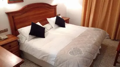 a bedroom with a bed with white sheets and black pillows at Hotel Bonilla in La Barca de la Florida