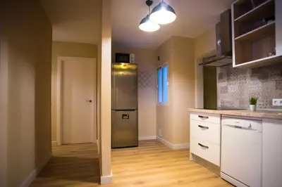a kitchen with a stainless steel refrigerator and wooden floors at Santo Tomás A Ha Apartment in Cádiz