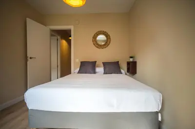 a large white bed in a bedroom with a mirror at Santo Tomás A Ha Apartment in Cádiz