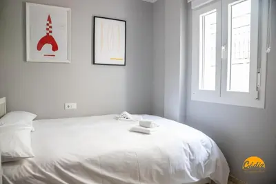 a white bedroom with a white bed with two windows at Casa Arcoiris by Cadiz Time in Cádiz