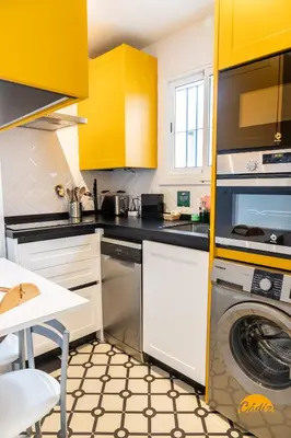 a kitchen with yellow cabinets and a washing machine at Casa Arcoiris by Cadiz Time in Cádiz