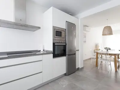 a kitchen with a stainless steel refrigerator and a table at La Fontanilla Place in Conil de la Frontera