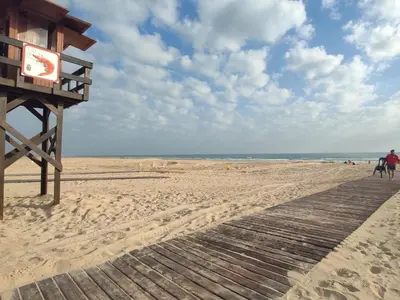 a boardwalk on a beach with a sign on it at La Fontanilla Place in Conil de la Frontera