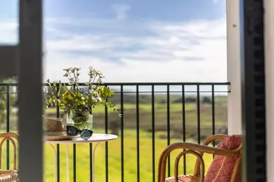 a table with a vase of flowers on a balcony at Hotel Marhava in Conil de la Frontera