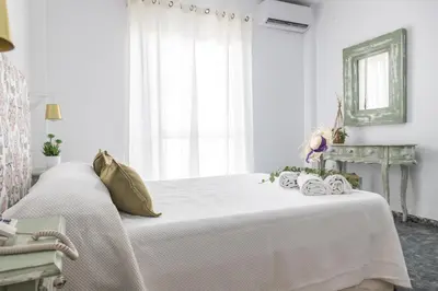 a white bedroom with a large bed with white curtains at Hotel Marhava in Conil de la Frontera