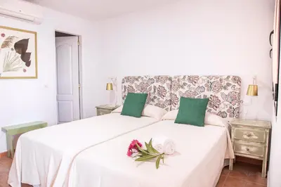 a white bedroom with two beds with flowers on them at Hotel Marhava in Conil de la Frontera
