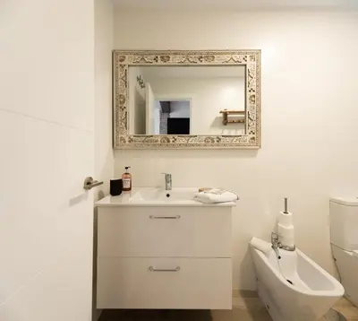 a white bathroom with a sink and a mirror at Apartamento Entrecatedrales in Cádiz