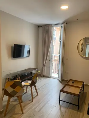 a living room with a table and a tv on the wall at Apartamento Entrecatedrales 2 in Cádiz