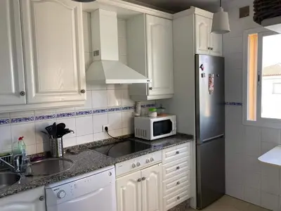 a kitchen with white cabinets and a sink and a microwave at Apartamento Ailem in Novo Sancti Petri