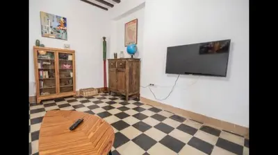 a living room with a tv on the wall and a table at APARTAMENTO LA MODERNA in Cádiz