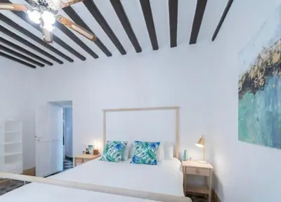 a bedroom with a white bed with blue pillows at APARTAMENTO LA MODERNA in Cádiz
