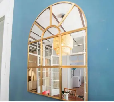 a mirror reflecting a room with a table and a chair at APARTAMENTO LA MODERNA in Cádiz