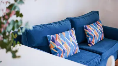 a blue couch with two colorful pillows on it at Jardín del Golf Nº 36 by Fontanilla del Mar Holidays Rentals in Chiclana de la Frontera