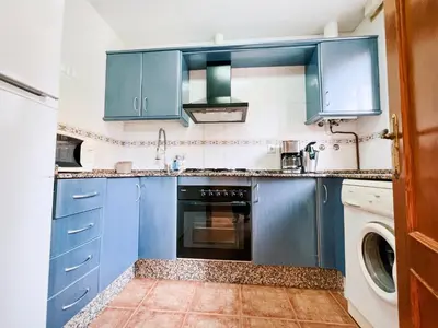 a kitchen with blue cabinets and a washer and dryer at Jardín del Golf Nº 36 by Fontanilla del Mar Holidays Rentals in Chiclana de la Frontera