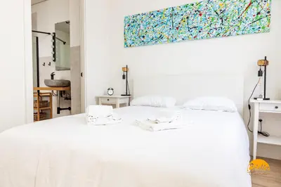 a white bed in a white bedroom with a painting on the wall at Tiles Home by Cadiz Time in Cádiz
