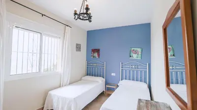 a room with two beds and a blue wall at Casa Rural Los Garrovillos by Fontanilla del Mar Holidays Rentals in Conil de la Frontera