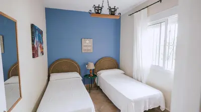 two beds in a room with a blue wall at Casa Rural Los Garrovillos by Fontanilla del Mar Holidays Rentals in Conil de la Frontera