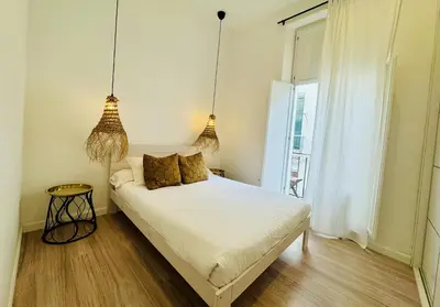 a bedroom with a bed and two pendant lights at MANA home Keep calm feel the light and shine in Cádiz