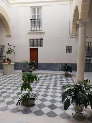 a courtyard with a checkered floor and plants in a building at La Casona de Rances Grupo AC Gestion in Cádiz