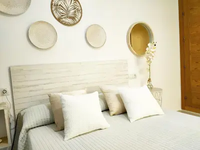 a bedroom with a bed with white pillows and mirrors at RELAX CHICLANA-Aparcamiento privado-TV Cable-WifiPlus-Aire Acond-Incluido in Chiclana de la Frontera