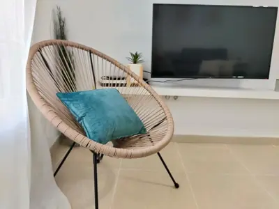 a wicker chair with a blue pillow in a room at RELAX CHICLANA-Aparcamiento privado-TV Cable-WifiPlus-Aire Acond-Incluido in Chiclana de la Frontera