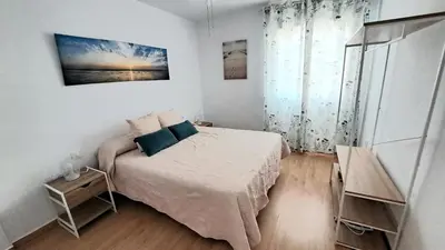 a white bedroom with a bed and a window at Apartamento Playa La Barrosa in Chiclana de la Frontera