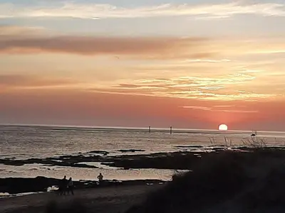 a sunset at the beach with people on the beach at Apartamento Playa La Barrosa in Chiclana de la Frontera