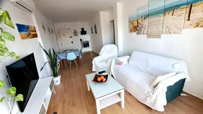 a living room with a white couch and a table at Apartamento Playa La Barrosa in Chiclana de la Frontera