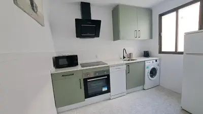 a kitchen with green cabinets and a washer and dryer at Apartamento Playa La Barrosa in Chiclana de la Frontera