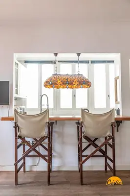 a dining room table with two chairs and a chandelier at La Bella Escondida by Cadiz Time in Cádiz