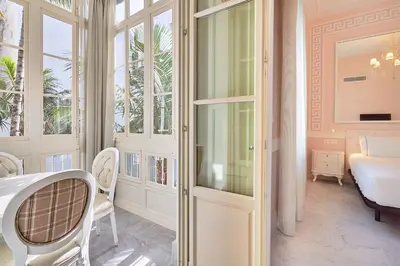a room with a table and chairs and a bedroom at Tandem Palacio Veedor de Galeras Suites in Cádiz