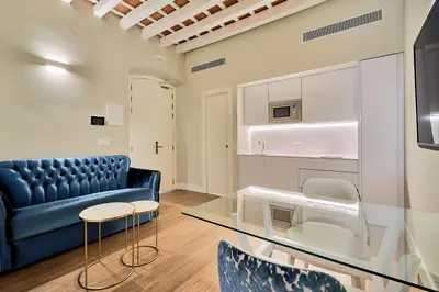 a living room with a blue couch and a glass table at Tandem Palacio Veedor de Galeras Suites in Cádiz