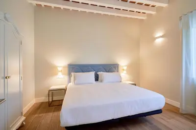 a bedroom with a large white bed with two pillows at Tandem Palacio Veedor de Galeras Suites in Cádiz
