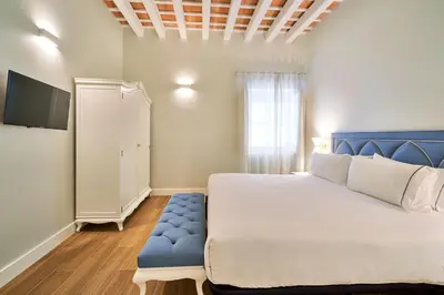 a bedroom with a white bed and a blue bench at Tandem Palacio Veedor de Galeras Suites in Cádiz