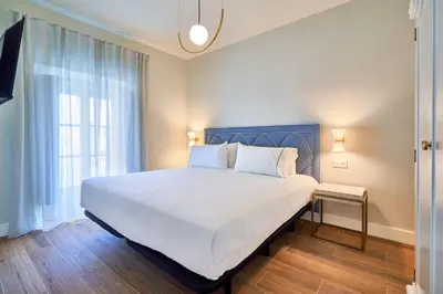 a bedroom with a large white bed and a window at Tandem Palacio Veedor de Galeras Suites in Cádiz